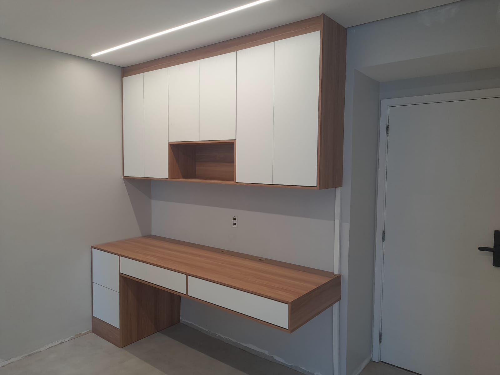 Home office com bancada suspensa e armário aéreo em branco e madeira